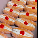 Mini Fresh Cream Donuts                                                                                                                          400g flour 200ml warm milk 7g yeast 40g castor sugar 1/4 teaspoon salt 1 egg, plus 1 egg yolk 45 g butter Oil. 1 cup castor sugar for coating 2 cups whipped cream( beaten with 1/3 cup caster sugar until stiff) 6 Glacéd cherries Put flour into a bowl, make a well in the centre. Add warm milk, yeast and sugar to it. Mix it into the milk. Bring a bit of flour from the sides and mix until you have a paste. While still not mixing all the flour in. Cover and rest for 20 to 30 mins. Once done, add the egg and egg yolk, salt and butter to it and mix until you form a dough. Knead for 8 mins until smooth and elastic. Place in a bowl and cover as proof until double in volume for 30 to 40 mins. Once done, roll out and divide into 12 pieces and roll each into a smooth ball and then into a long roll. Place on a floured tray and let it rise for 20 to 30 mins until double in volume. Heat oil on medium and fry until both sides are lightly golden brown having a sign of a well made donut on it. Which is the white ring around it. Allow to cool. Roll in castor sugar, cut in half not fully through and pipe whipped cream and decorate with glacéd cherries.